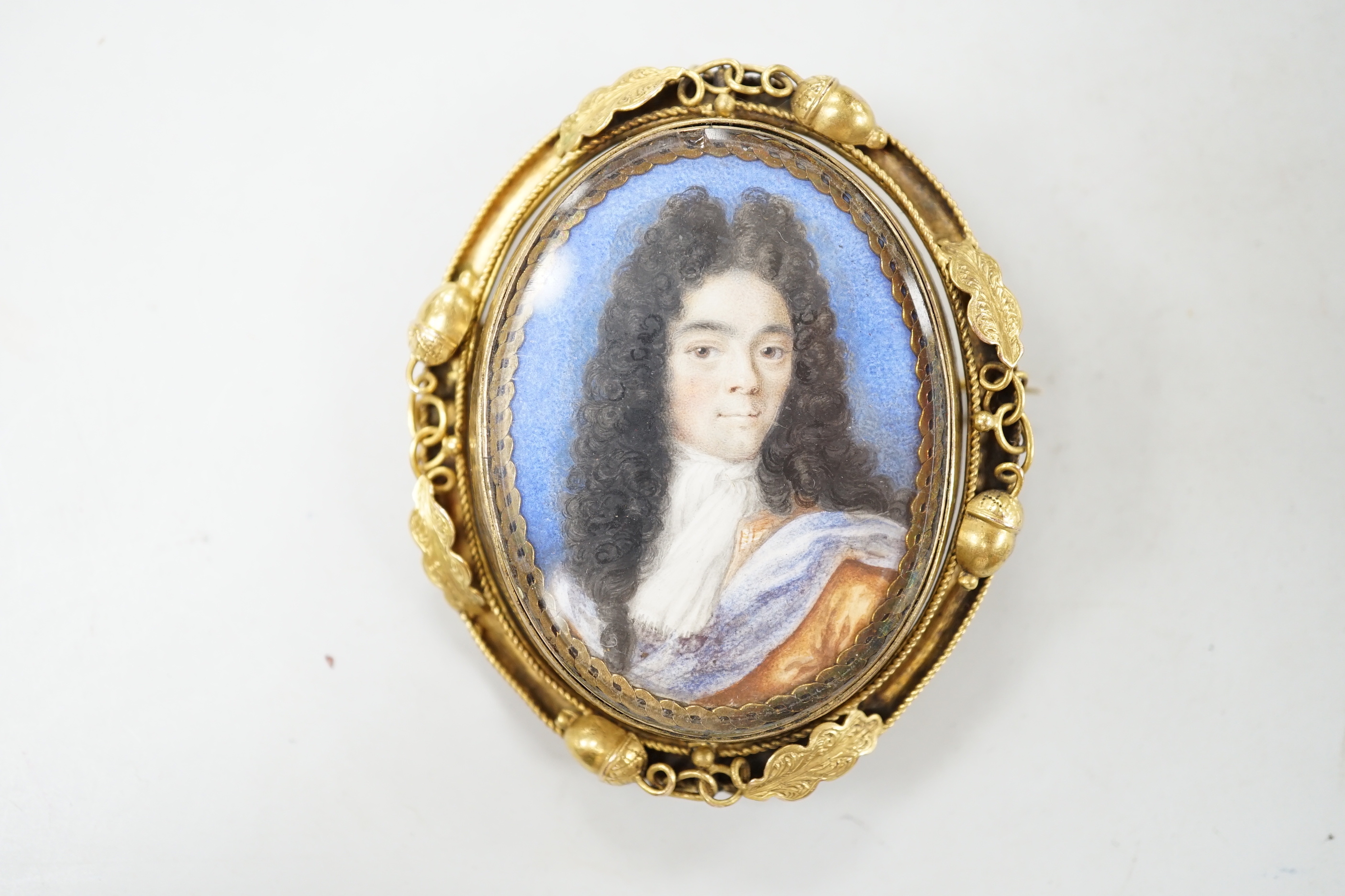 A Georgian yellow metal mounted oval portrait watercolour of a gentleman, with acorn and leaf border, 58mm.